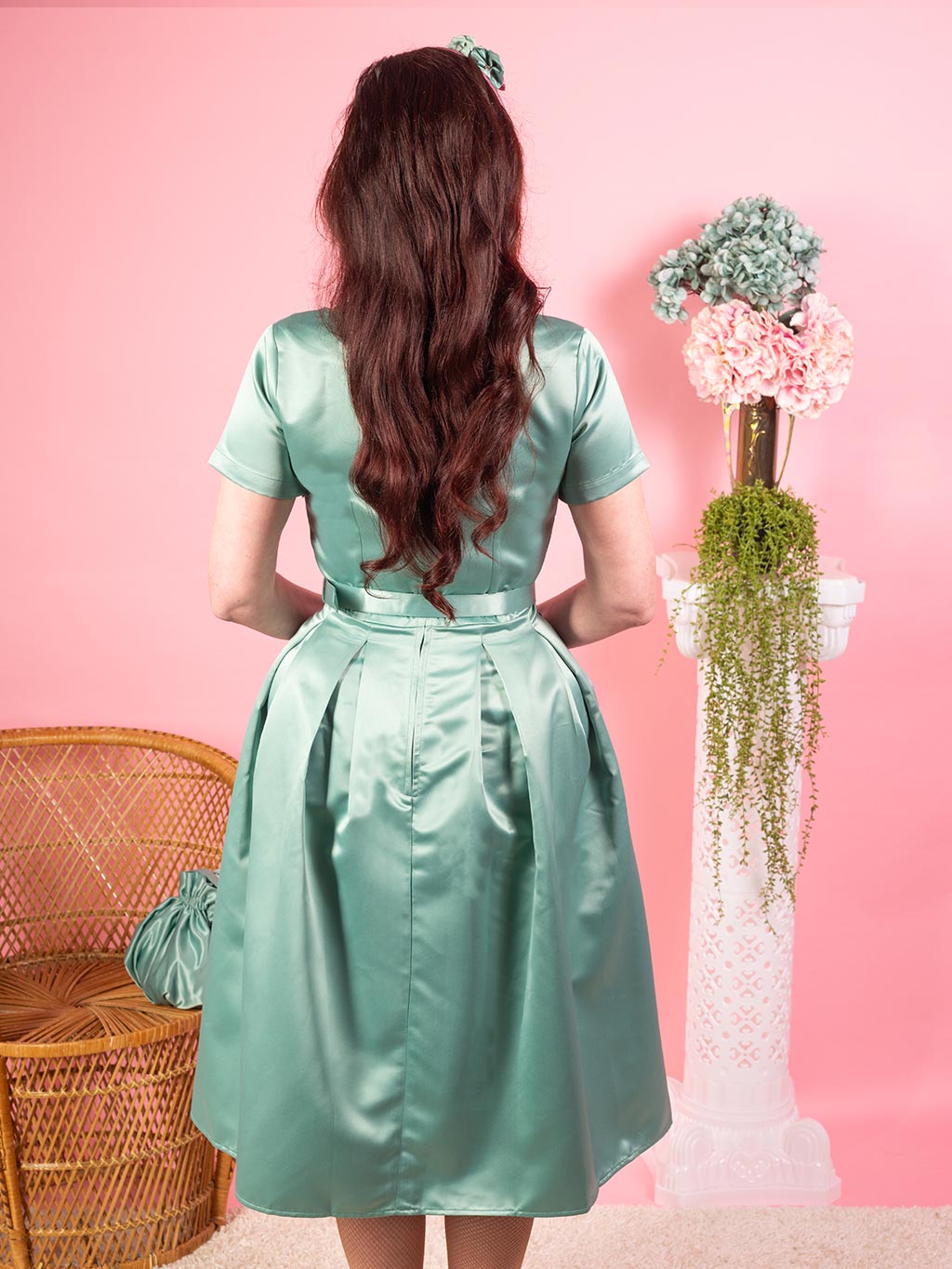 Back view of a 1950s pleated dress in pastel sage green satin