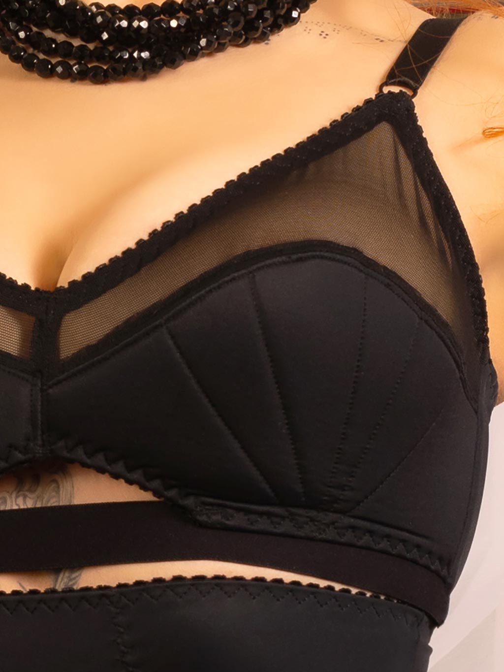 Close-up of black retro bra detailing, featuring vintage-style lower cup stitching and sheer top panel