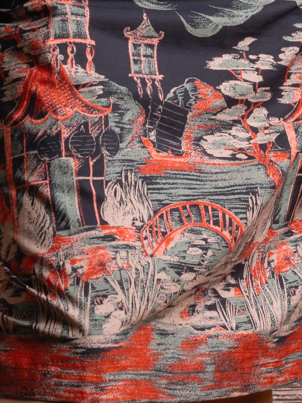 Close-up of Pagoda border print detail showing copper and sage green pagodas on black cotton fabric